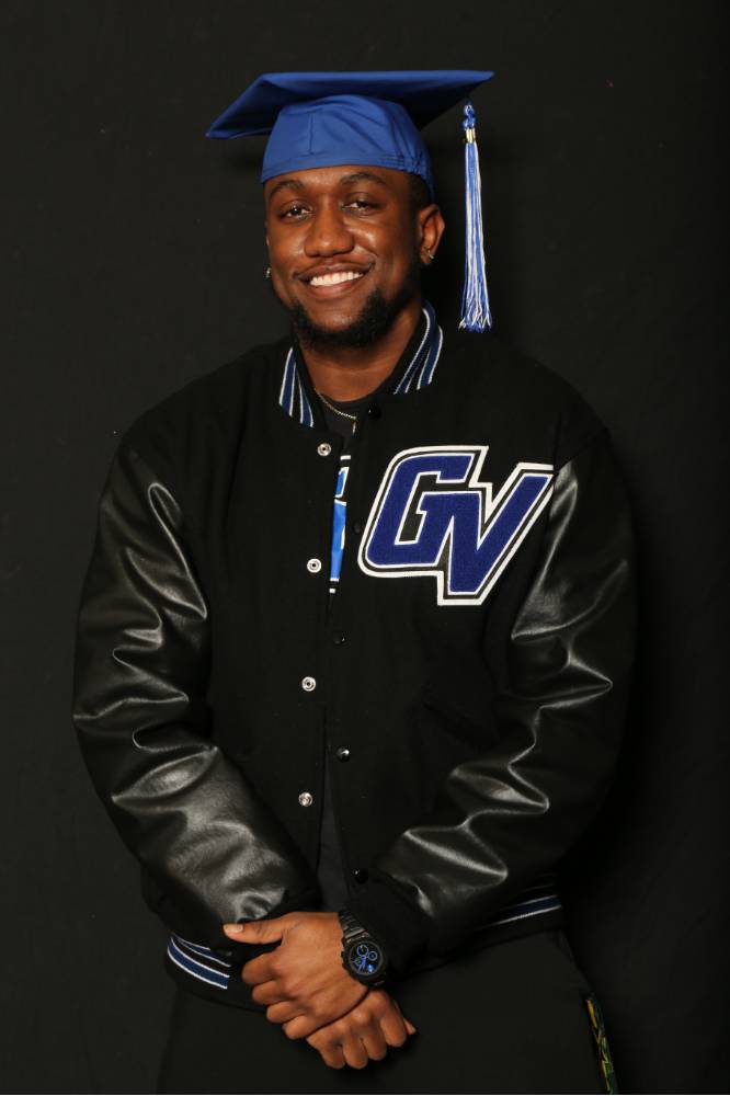 man with graduation cap and gvsu varsity jacket smiling for photo